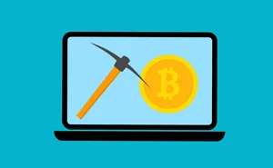 Cartoon laptop with a pickaxe and coins, symbolising crypto mining
